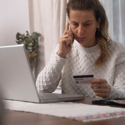 Woman on phone looking at credit card