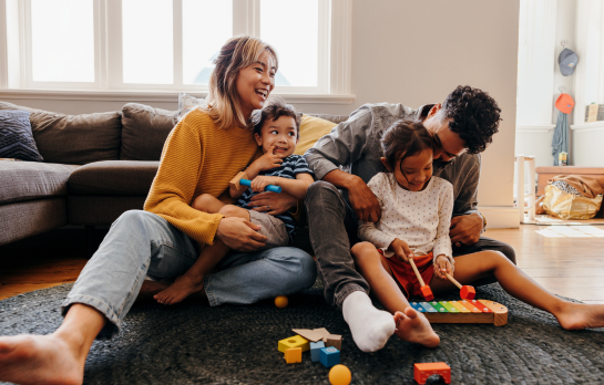 mom dad and two kids playing in living room 