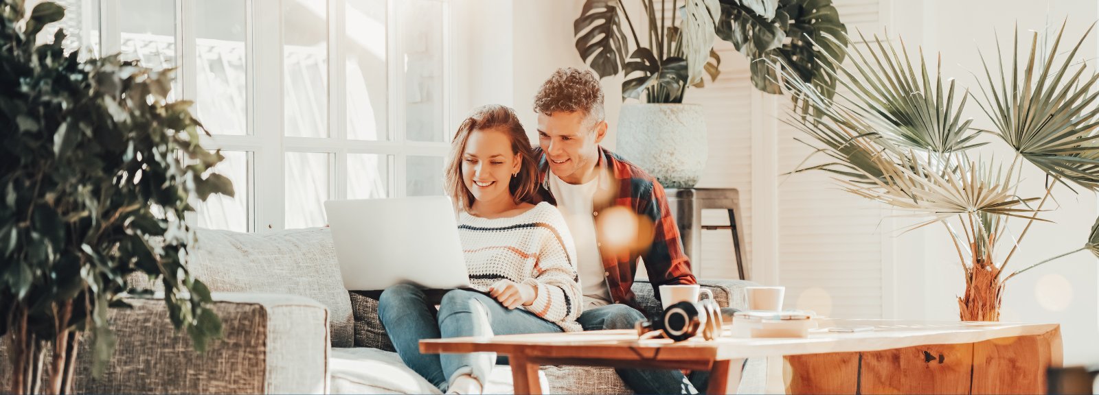 Man and woman look at laptop in living room